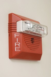Red fire alarm mounted on white wall