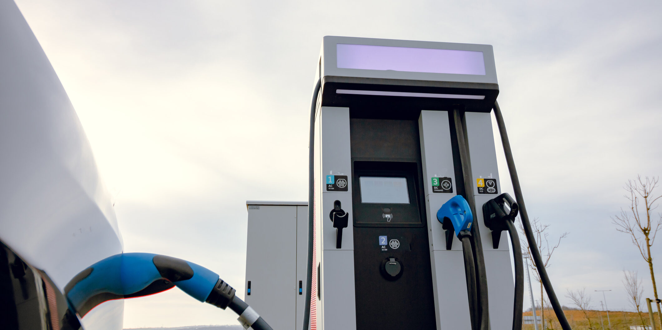 Electric car fast charging near the EV charging station. Plugged in electric car to the fast charger. EV charging station.